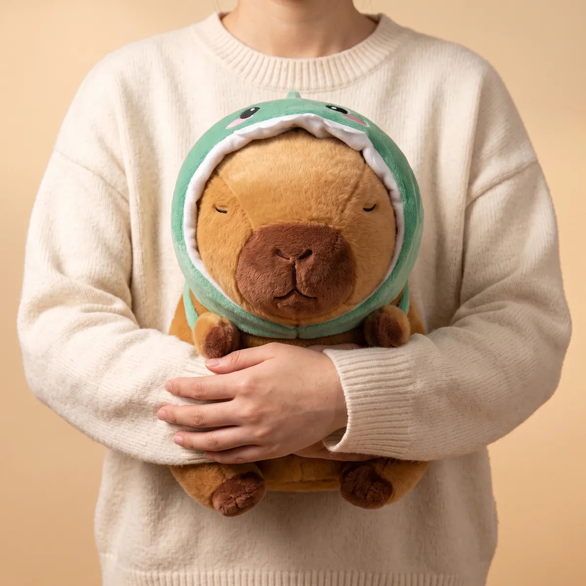 Person holding the dino capybara plush against a sweater