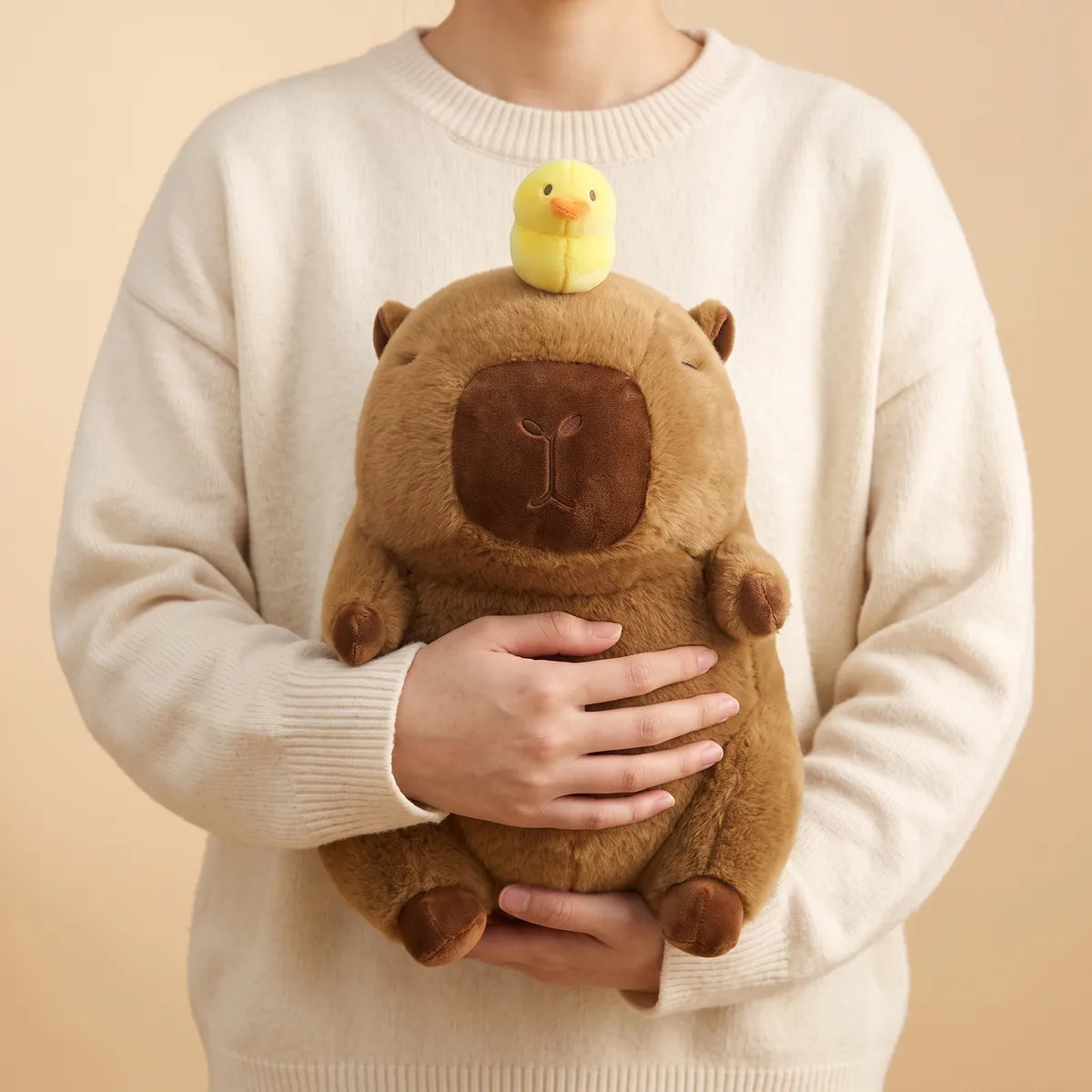 Capybara with duck on head plush held against a chest, the lemon yellow duckling sitting level with the collar