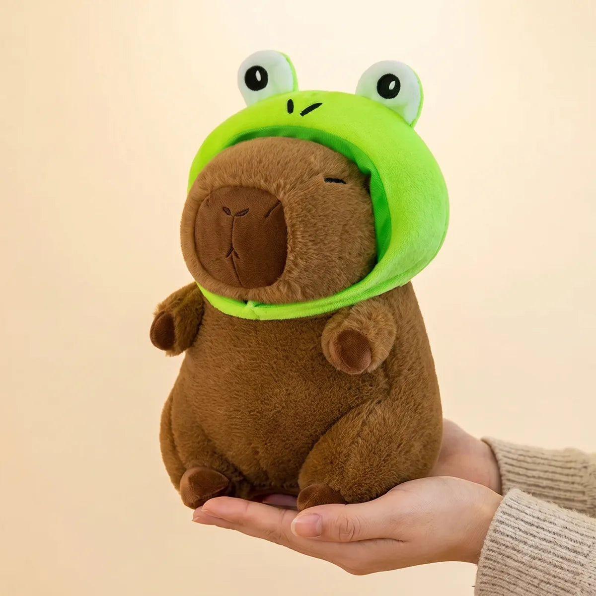 Hands cradling the 9 in (22 cm) frog capybara plush to show its real size