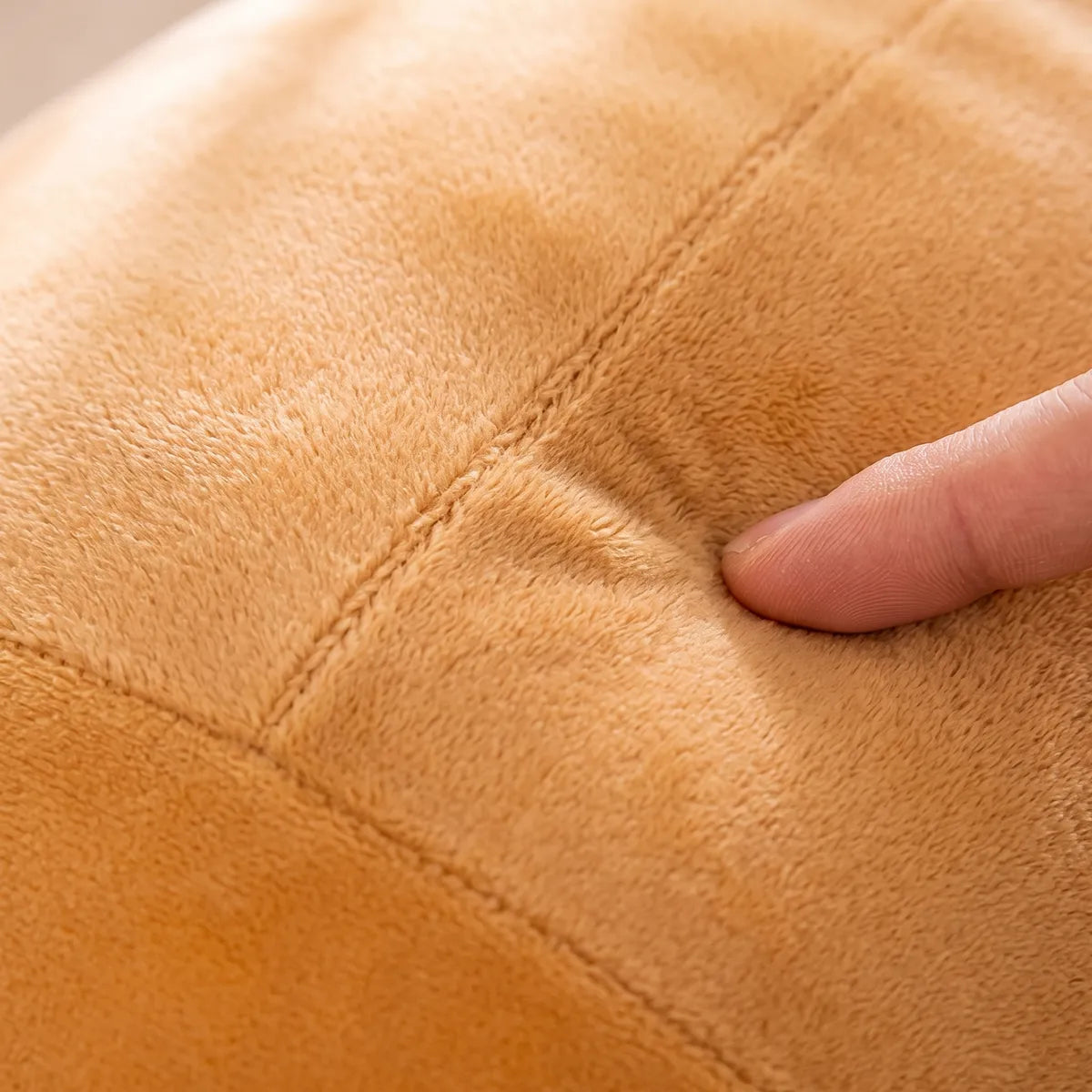 Fingertip pressing the smooth short pile fur of the giant capybara plush