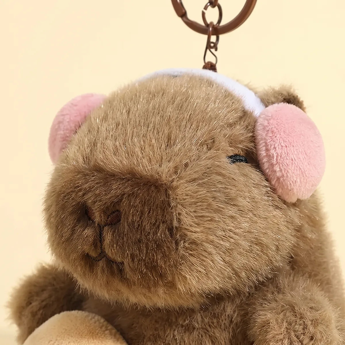 Close up of the embroidered acoustic guitar and pink headphones on the capybara keychain