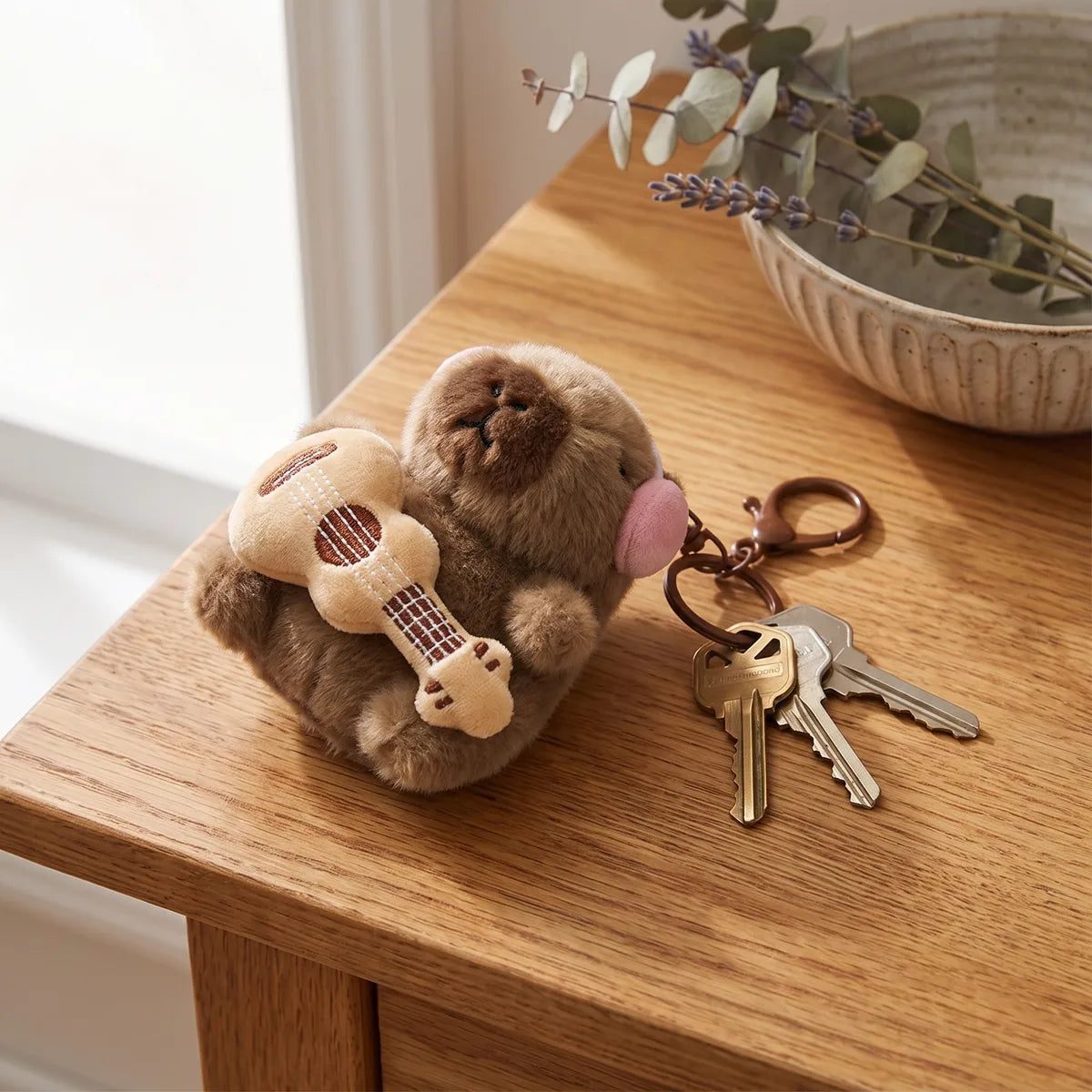 Guitar capybara keychain lying on a wooden table