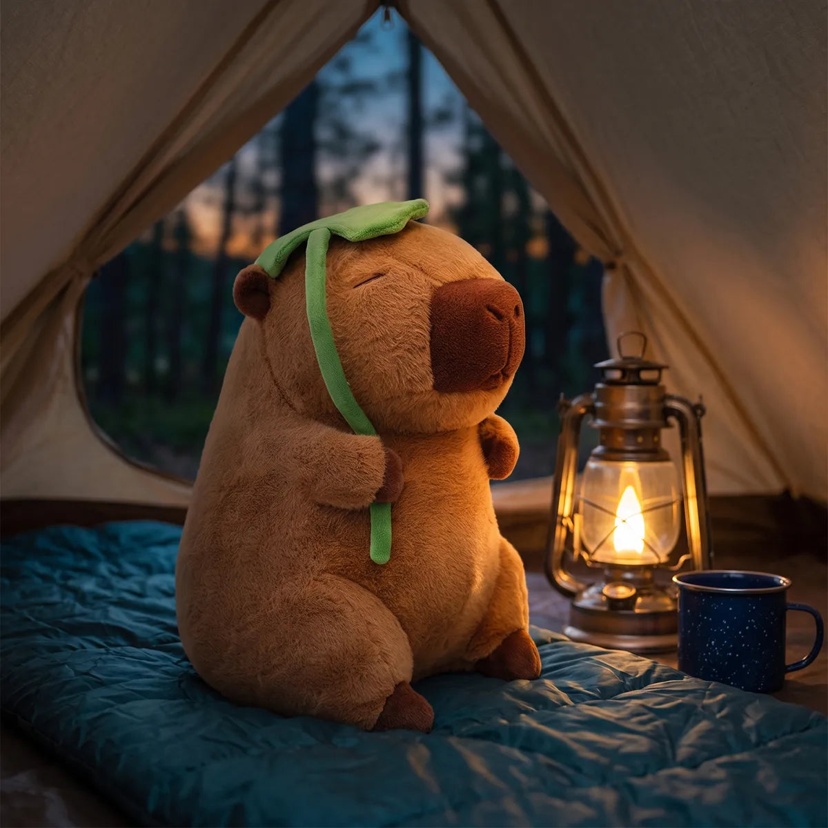 Jumbo capybara plush sitting on a sleeping bag inside a tent at dusk next to a lit lantern.