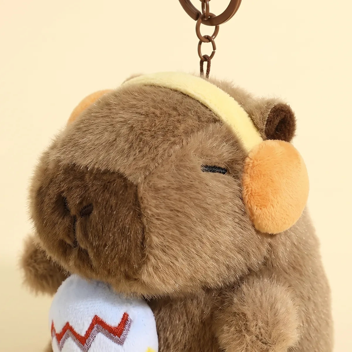 Close up of the embroidered microphone and ear cups on the capybara keychain