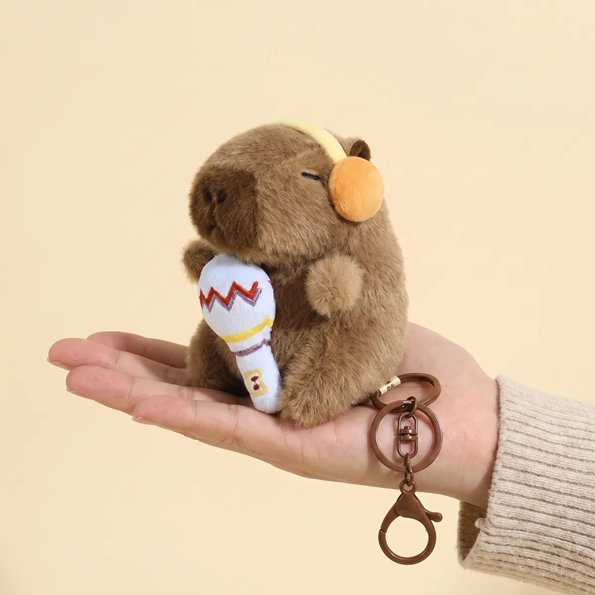 Microphone capybara keychain held in a hand to show its 4 in size