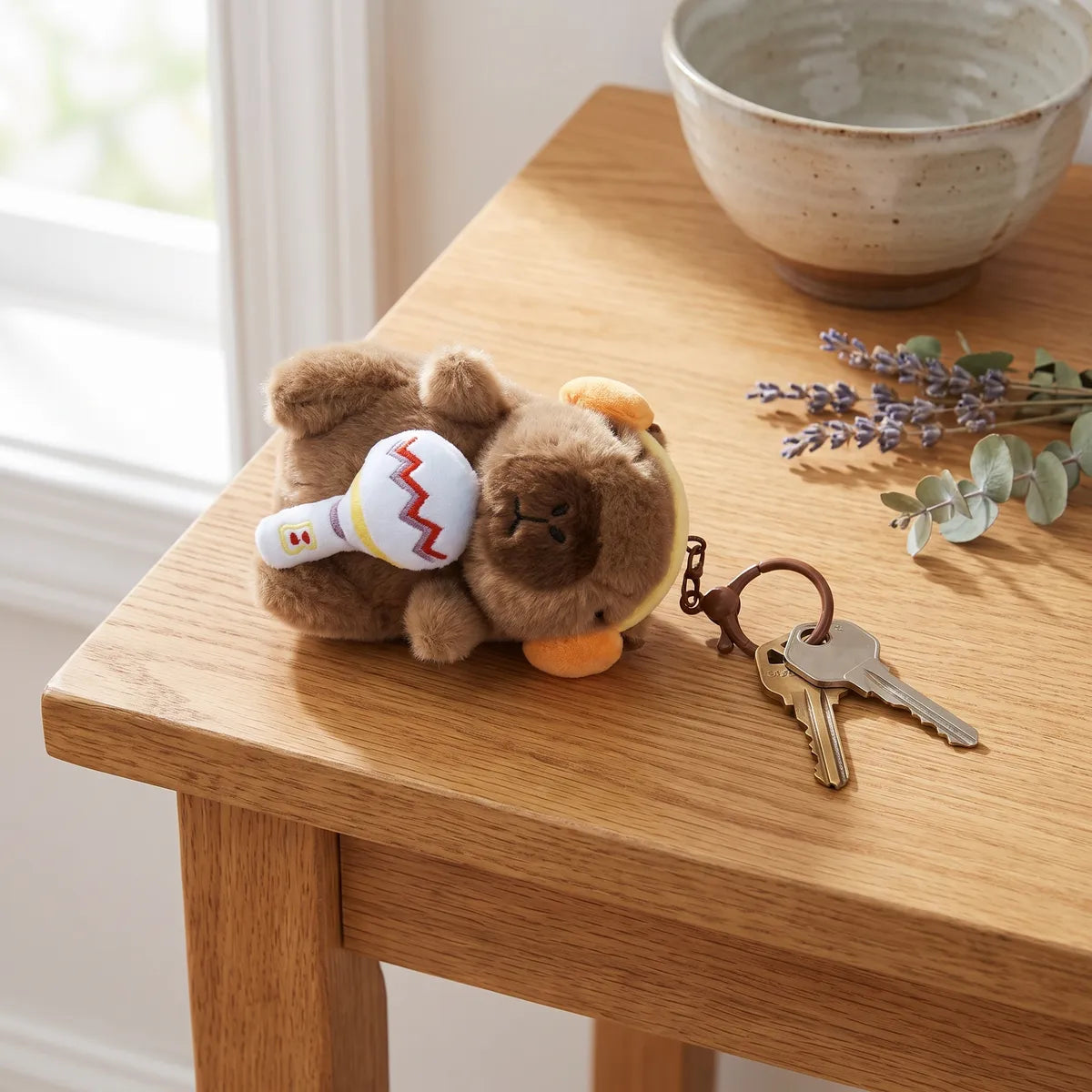 Microphone capybara keychain lying on a wooden table