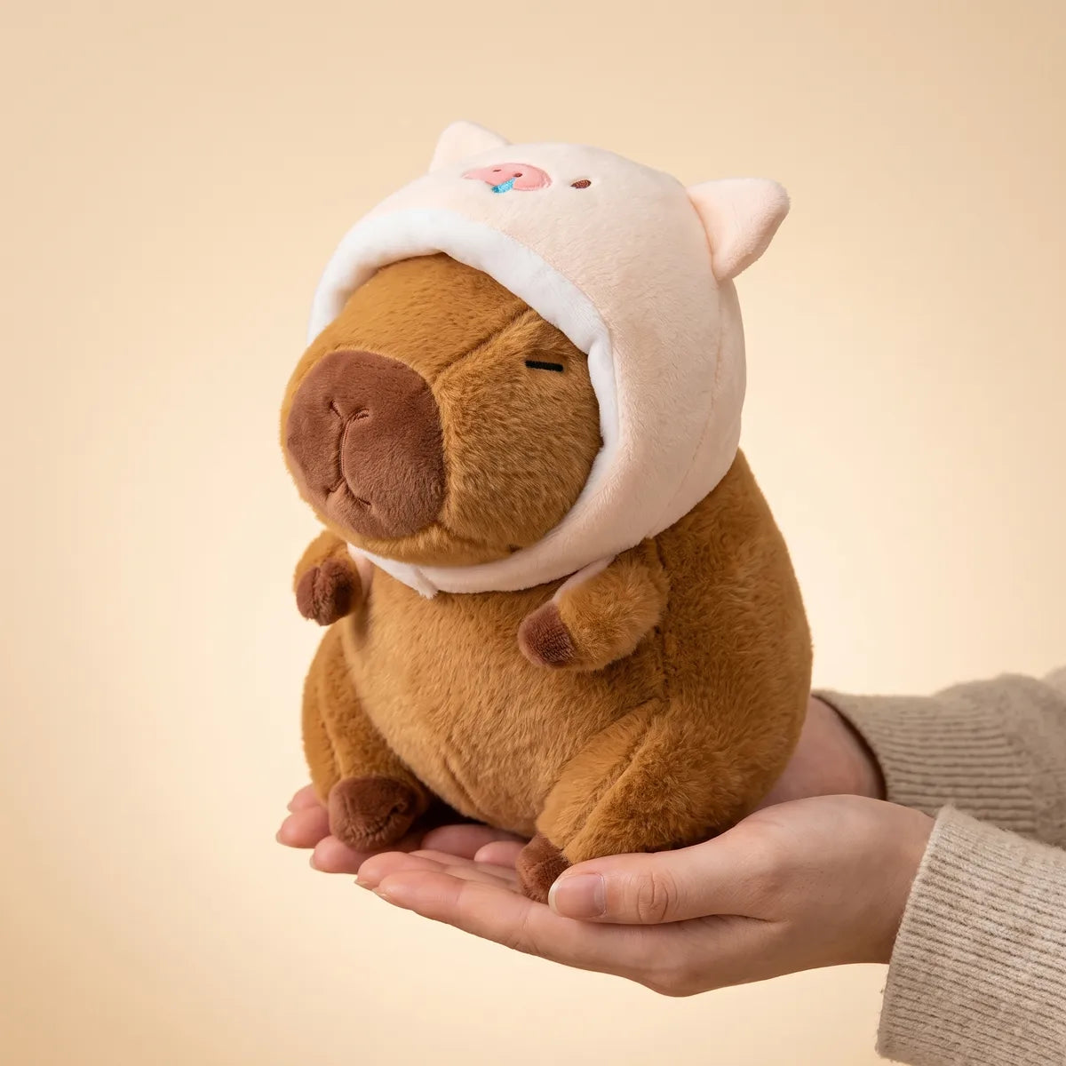 Hands cradling the piggy capybara plush to show its real size