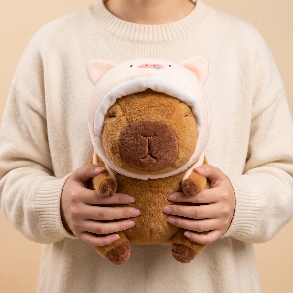Person holding the piggy capybara plush against a sweater