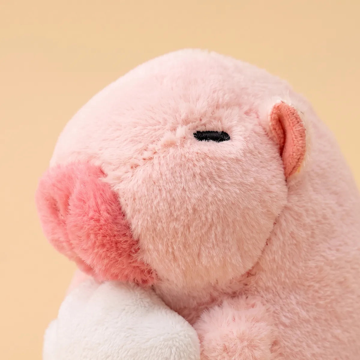 Close-up of the pink mini capybara plush face showing the stitched eye and deeper rose snout