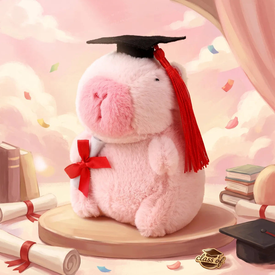 Pink graduation capybara plush in a black mortarboard with a red tassel, posed in a pastel scene of books, scrolls and confetti