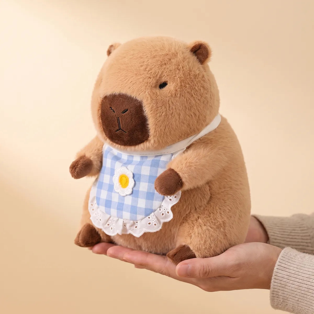 Hand holding the 12 in (30 cm) poop house capybara plush to show its real size
