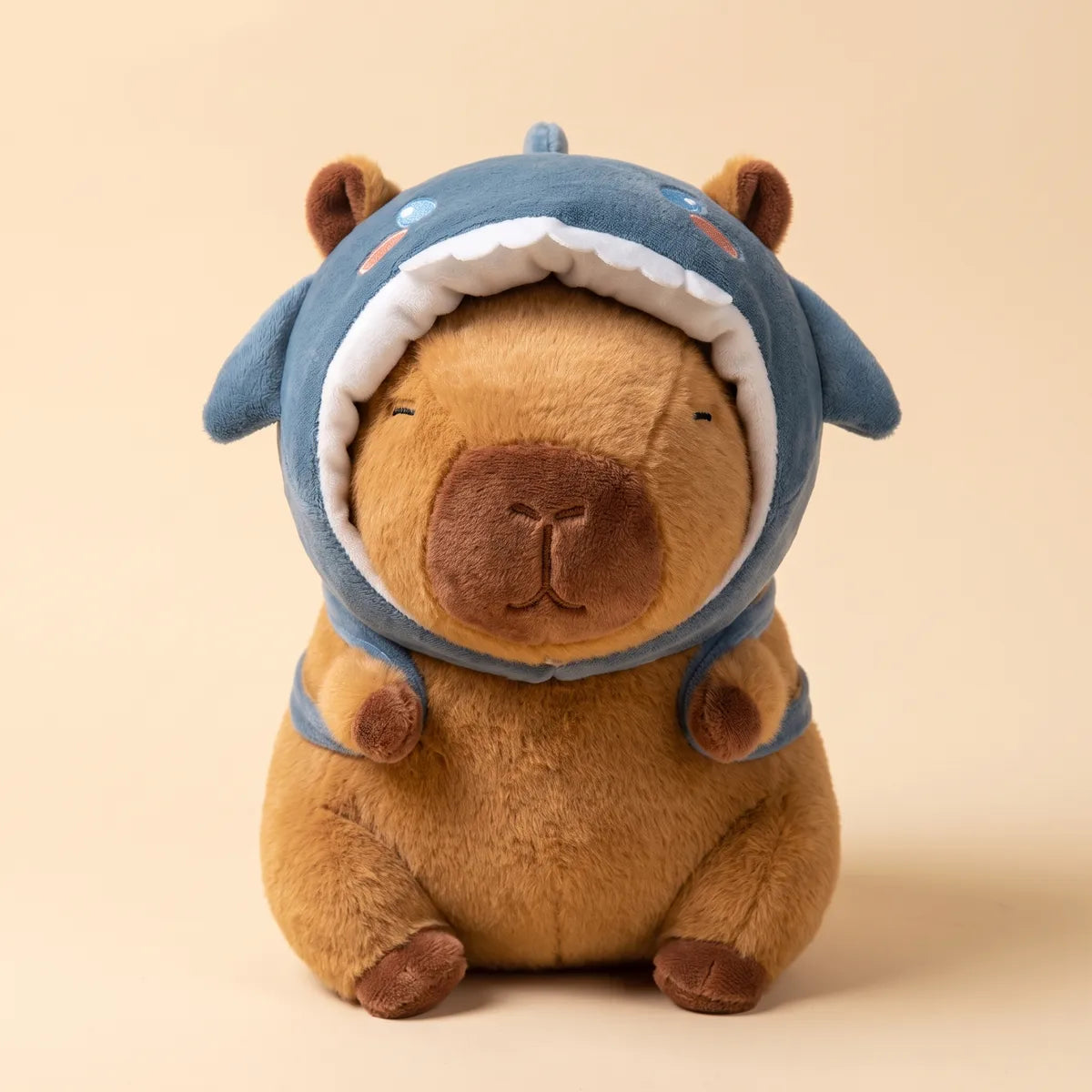 Brown capybara plush wearing its blue shark hood seen from the front