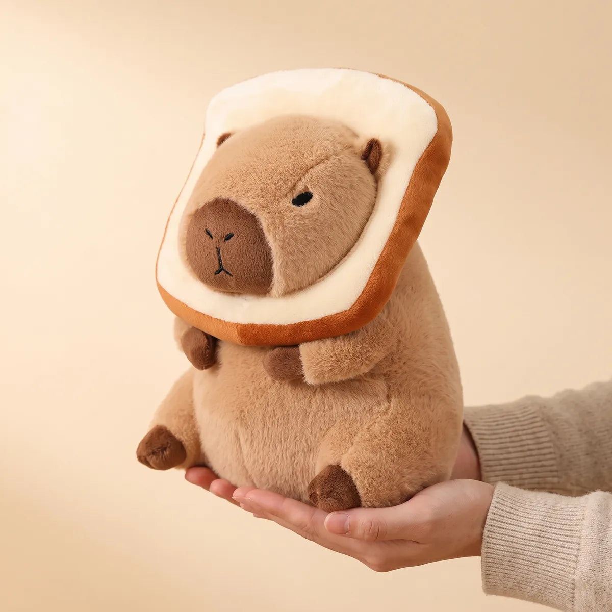 Hands cradling the 12 in (30 cm) slice of bread capybara plush to show its real size