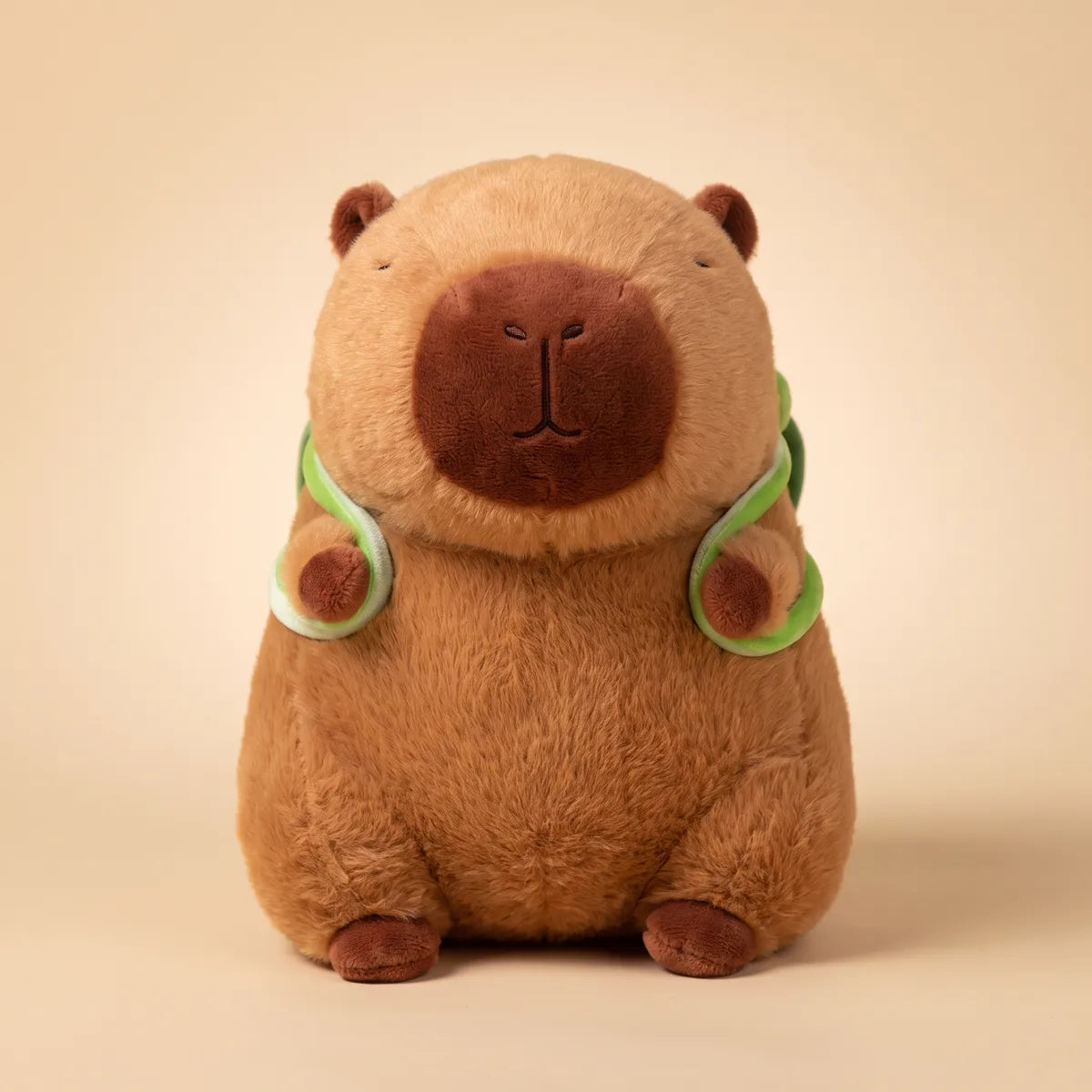 Brown turtle backpack capybara plush seen from the front with its green straps