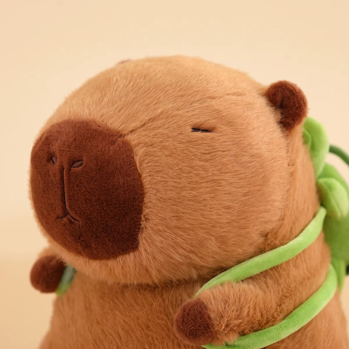 Close up of the capybara head and the green turtle strap over its shoulder