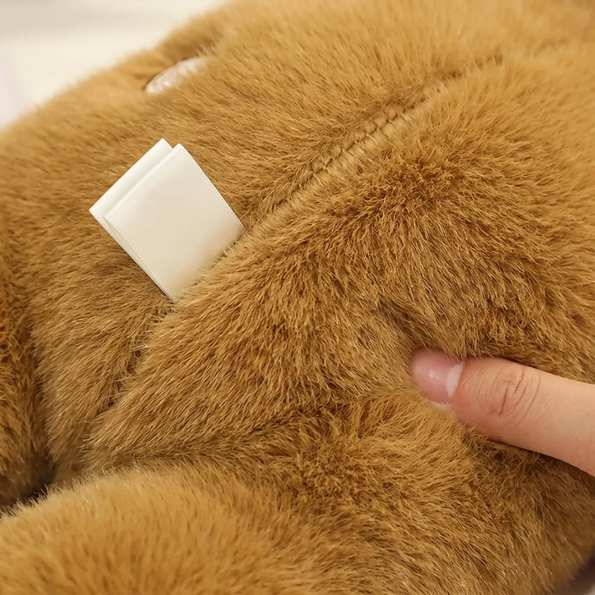 Fingertip pressing the dense fur of the weighted capybara plush