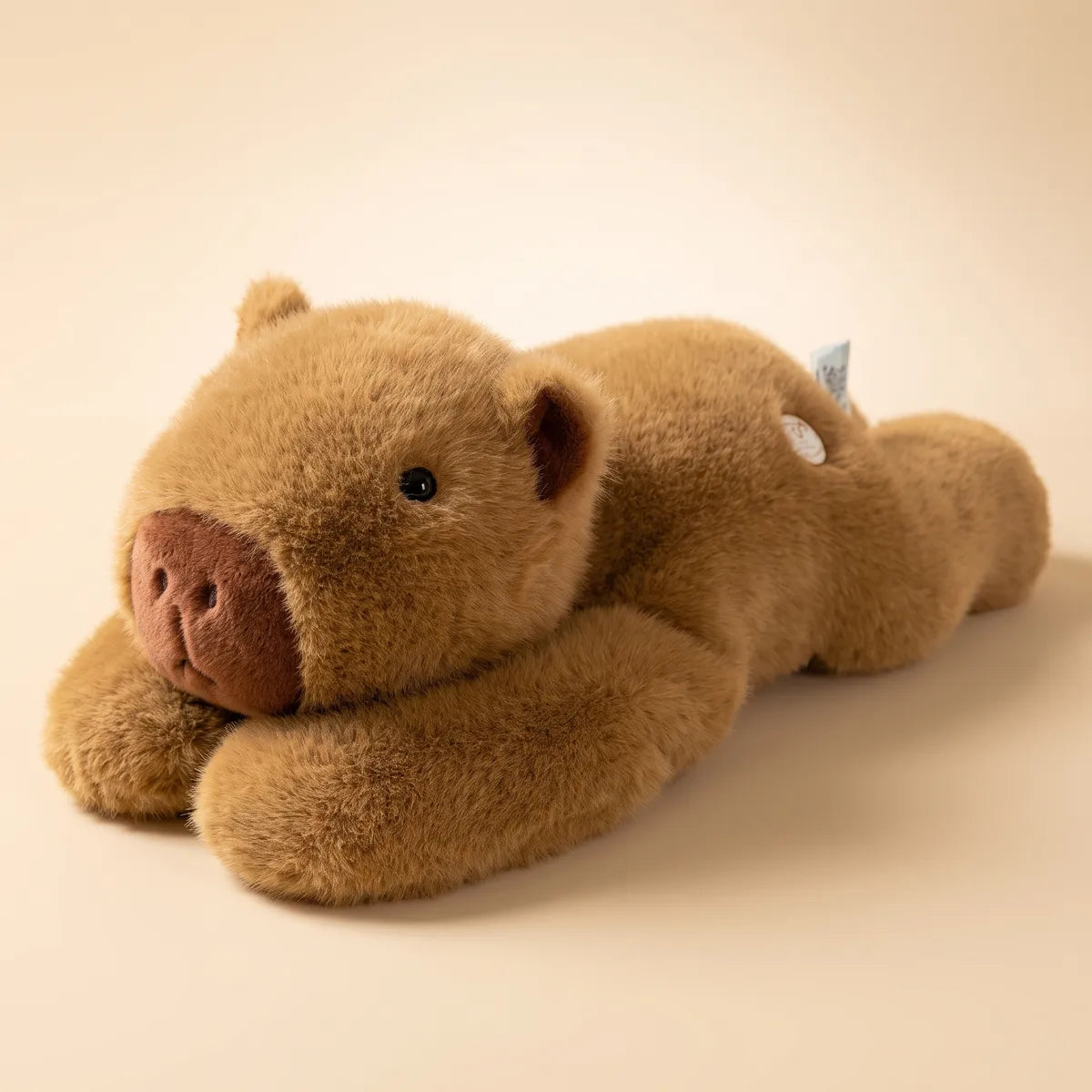 Honey brown weighted capybara plush lying flat with its muzzle on its front paws