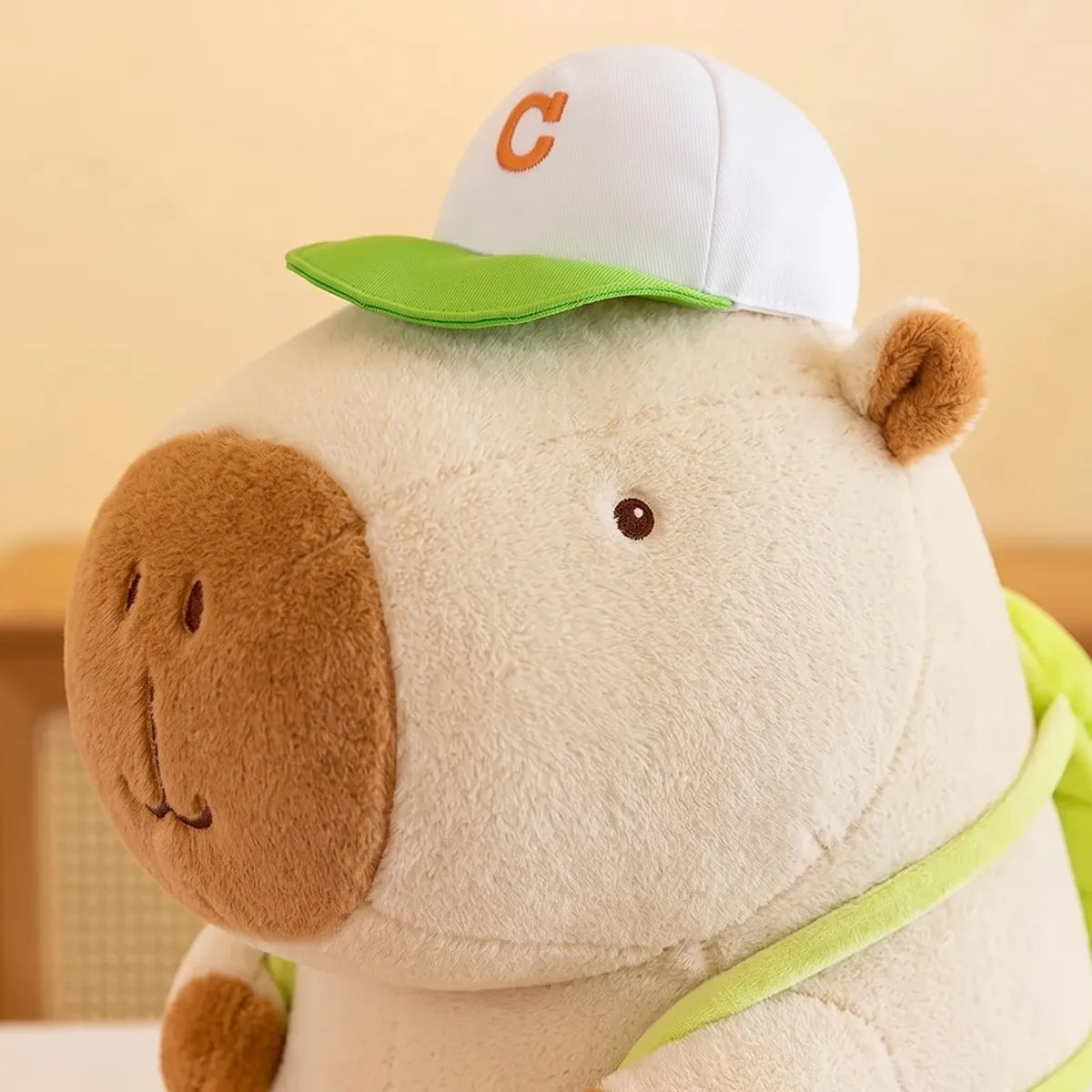 Close up of the green and white cap on the white tennis backpack capybara plush
